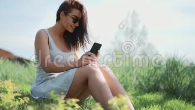 年轻的女人坐在草地上和朋友在公园里聊天。